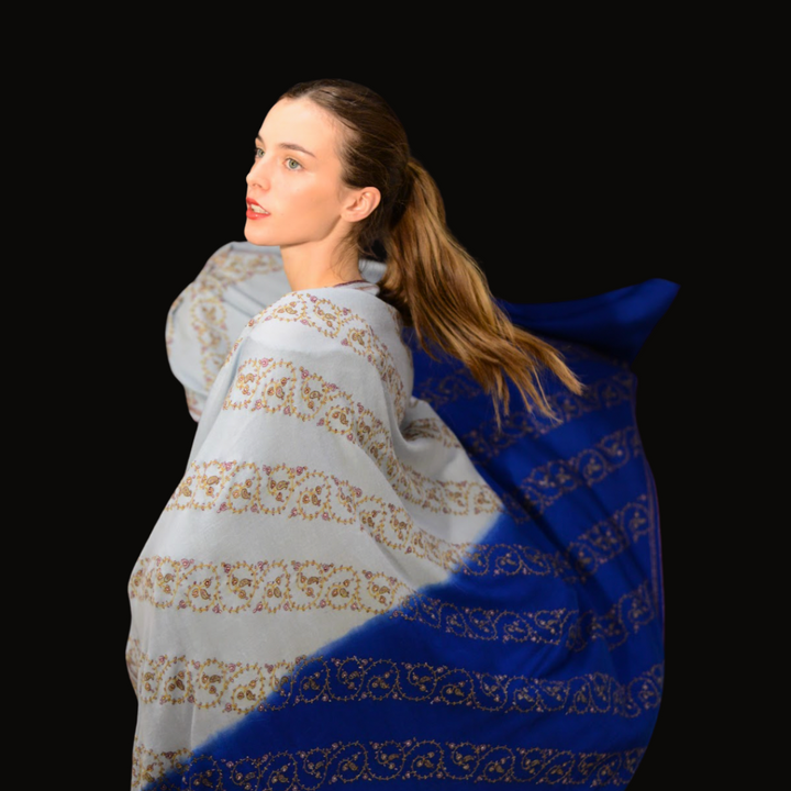 Woman wearing a blue and white patterned sozni pashmina  shawl on a black background