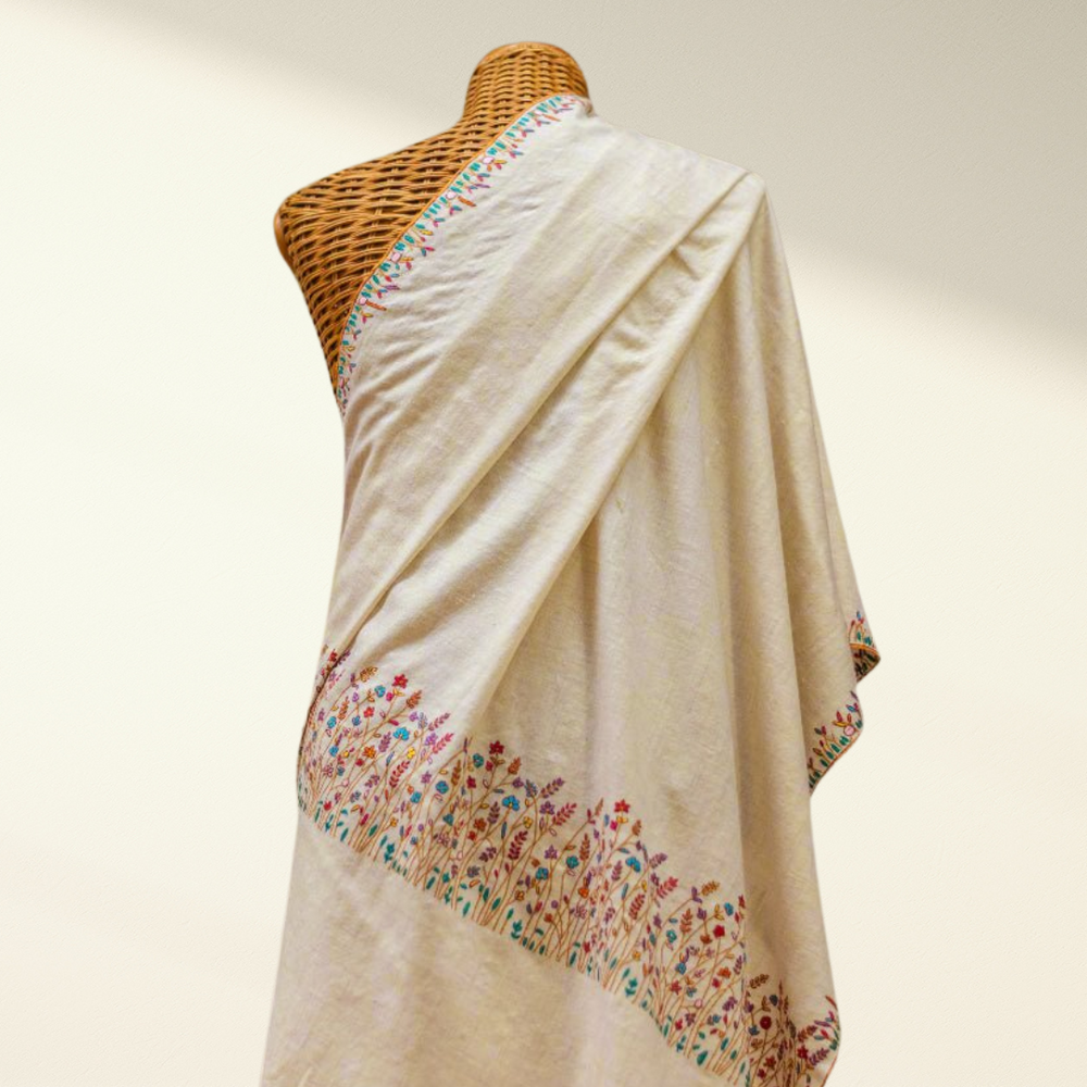 white pashmina shawl with floral embroidery on a mannequin against a neutral background