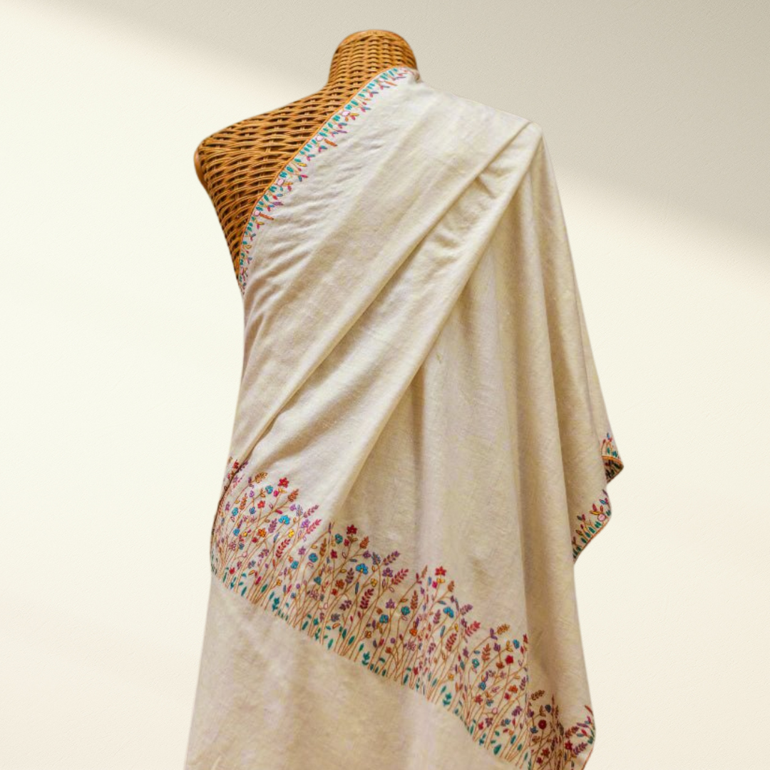 white pashmina shawl with floral embroidery on a mannequin against a neutral background
