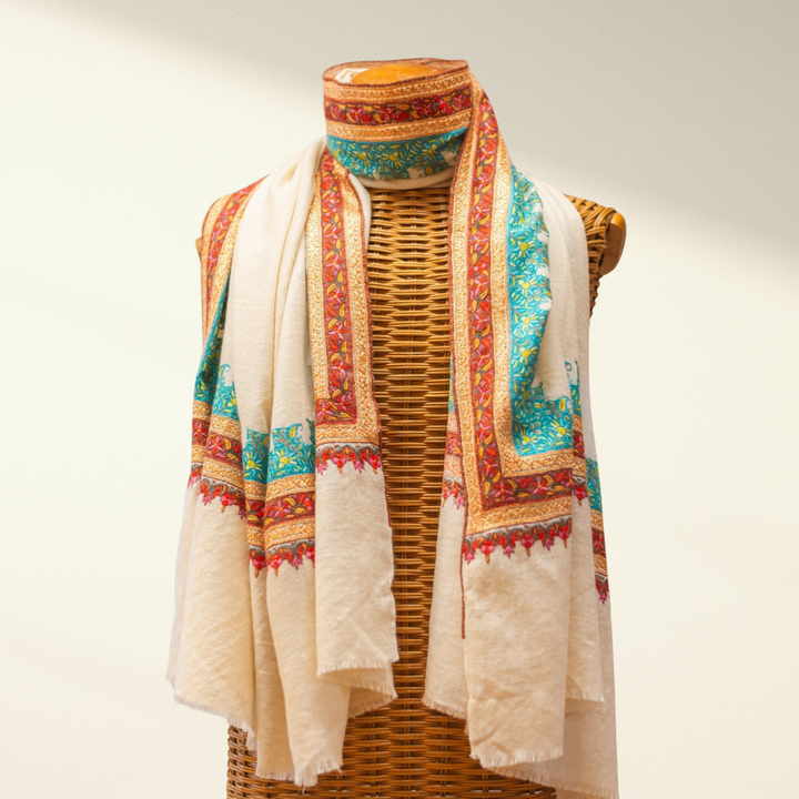 white pashmina shawl with patterns draped over a mannequin on a plain background